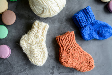 Colorful knitted socks and macaroons on a gray background