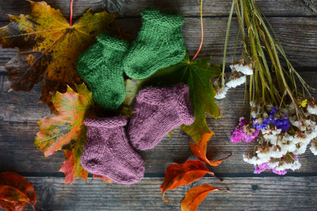 Woolen socks on a wooden background with autumn leaves and flowersの写真素材