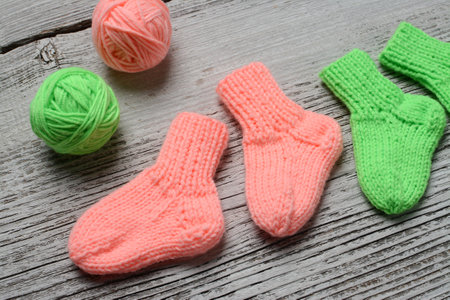 Knitted socks on a wooden background. Knitting needles and wool ballsの写真素材