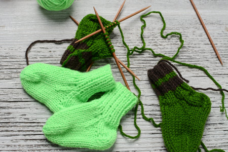 Knitted socks and needles on a wooden background. Knitting needles and socks.