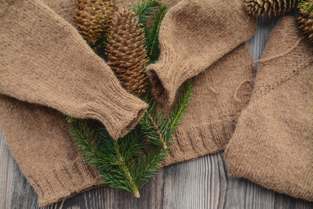 Fir tree branches and cones on handmade sweater on wooden background
