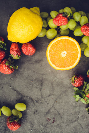 Strawberry, orange, grape and lemon on a grey backgroundの写真素材