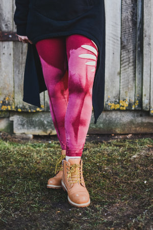 Fashionable young woman in red leggings and boots posing outdoorsの写真素材
