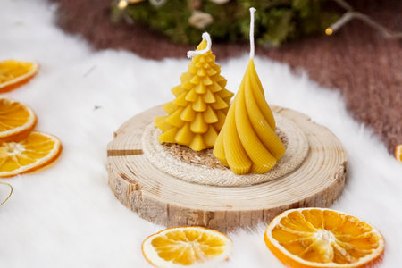 Christmas tree shaped candles and oranges on a wooden background with snowの写真素材