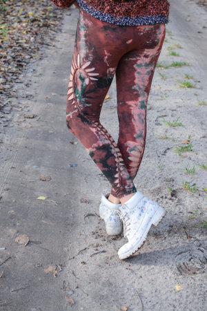 Female legs in colorful leggings and sneakers on the road.の写真素材