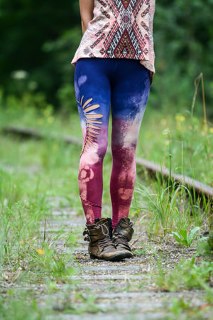 Legs of a young woman walking along a railroad track covered with paintの写真素材