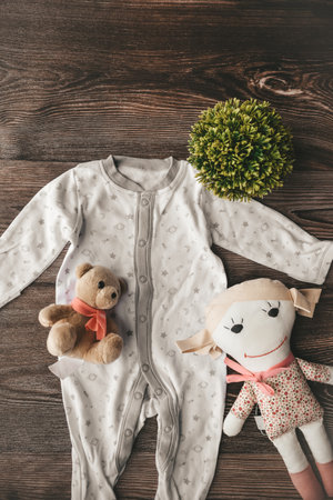 top view of cute child clothes and teddy bear on wooden backgroundの写真素材