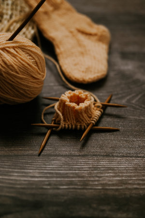Knitting needles, ball of yarn and socks on wooden backgroundの写真素材