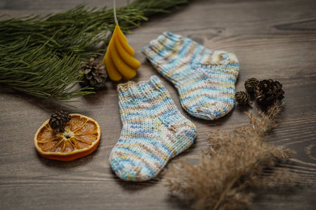 Christmas and New Year composition with knitted socks, fir branches and dried orange on wooden backgroundの写真素材