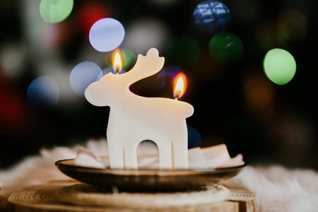 Christmas candle in the shape of a deer with bokeh backgroundの写真素材