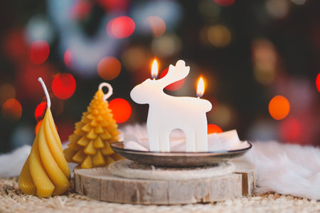Christmas candle with reindeer and christmas tree on bokeh backgroundの写真素材