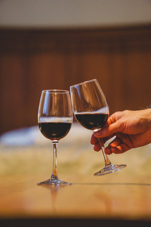 Two glasses of red wine on a wooden table in a luxury hotel roomの写真素材