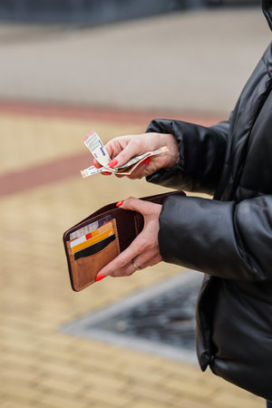 Woman in black leather jacket holding a wallet with money and credit cardsの写真素材