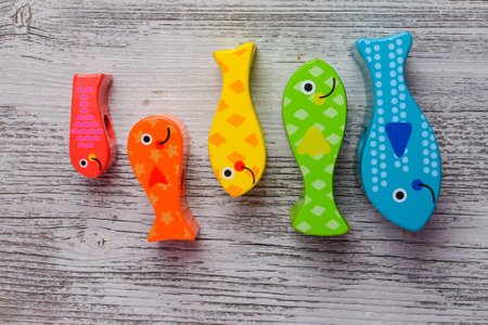 Funny colorful fish made of wood on a white wooden backgroundの写真素材