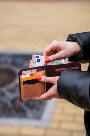Woman hands holding wallet with euro banknotes in the city park.の写真素材
