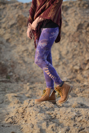A girl in a purple t-shirt and leggings walks on the sand.の写真素材