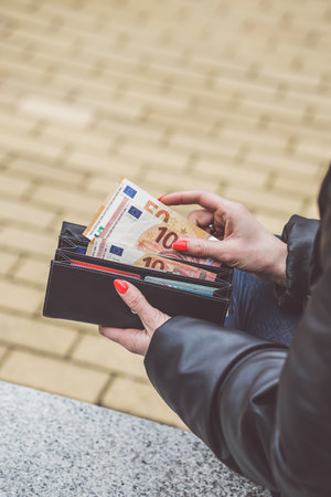 Woman hands holding a wallet full of euro banknotes on the streetの写真素材