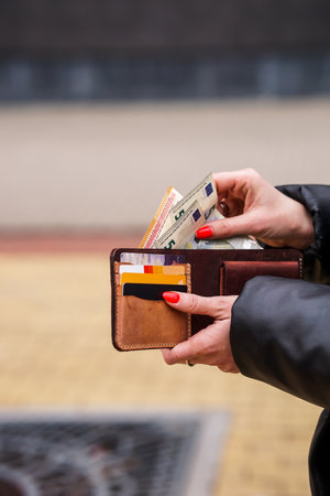 Female hands holding wallet with euro banknotes and credit cards in the cityの写真素材