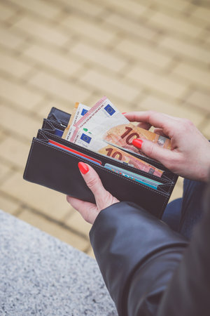 Close-up of a woman's hands holding a wallet full of moneyの写真素材
