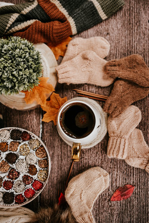 Cozy autumn composition with cup of hot tea, knitted scarf and knitted mittens on wooden backgroundの写真素材
