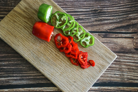 Sliced red and green bell pepper on wooden cutting board.