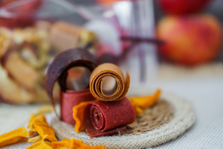 Freshly rolled, homemade fruit leather and dried fruit slices made from organic ingredients are displayed on a rustic tableの写真素材