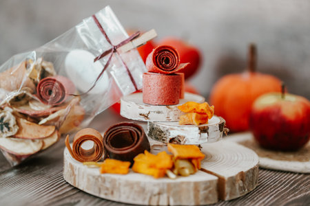 Freshly rolled, homemade fruit leather and dried fruit slices made from organic ingredients are displayed on a rustic tableの写真素材