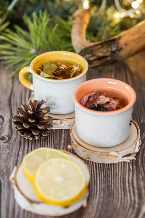 Cups of hot tea with lemon and pine cones on wooden backgroundの写真素材
