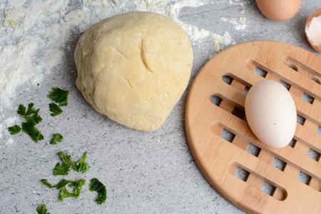 Preparation of dough for pizza with eggs and parsley on a cutting boardの写真素材