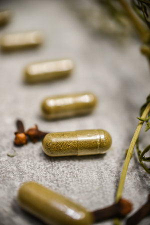 Herbal medicine capsules with herbs on rustic wooden background. Selective focus.の写真素材