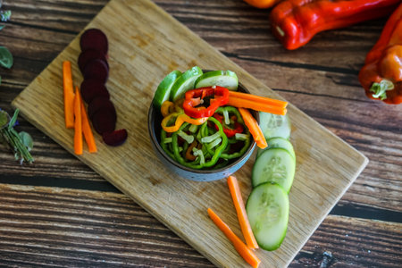 Fresh vegetable salad with carrot, cucumber, tomato and pepper on wooden backgroundの写真素材