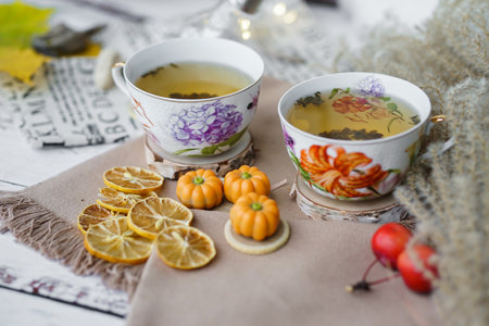 Cup of tea with lemon and autumn leaves on a wooden tableの写真素材