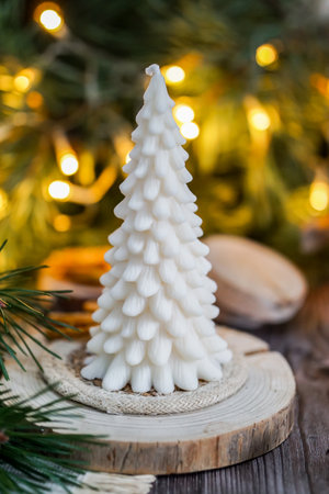 Beautiful soy wax candles in the room, decorated with fir tree branches, Christmas lights in the backgroundの写真素材