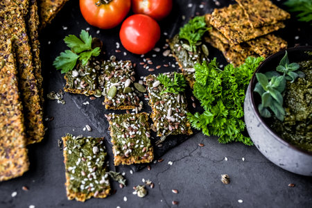 Healthy vegan crackers with pesto and herbs on dark backgroundの写真素材