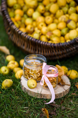 Preserved quince fruits in a wicker basket on the grassの写真素材