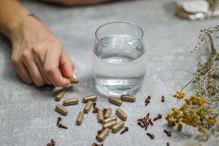Close-up of female hand holding pills and a glass of waterの写真素材