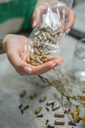 Woman hands holding handcrafted anti-parasitic detox capsules made with wormwood, clove, and a blend of natural herbs for holistic cleansingの写真素材