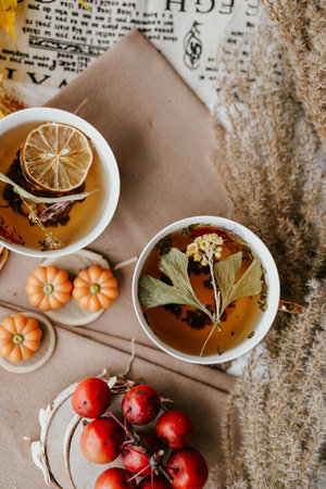 Cup of herbal tea with lemon and autumn leaves on wooden backgroundの写真素材