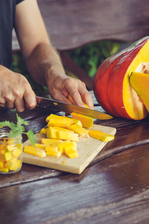 Man cuts pumpkin on a cutting board. Selective focus. nature.の写真素材
