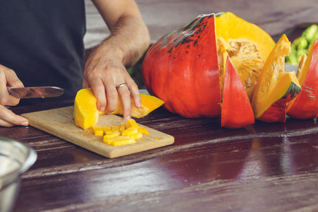 Hands of man cutting pumpkin on wooden tableの写真素材