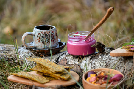 Healthy breakfast in the forest. A cup of hot coffee, a spoon and a jar of beetroot pesto.