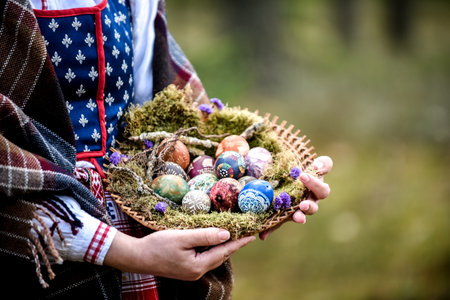 Easter eggs in a basket in the hands of a girl, wearing traditional Lithuanian clothes in the forest.の写真素材
