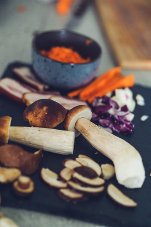 mushrooms on a cutting board with carrots and onions on a wooden tableの写真素材
