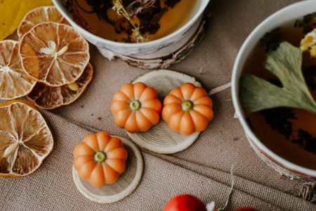 Autumn still life with pumpkin shaped candies and tea on sackcloth backgroundの写真素材