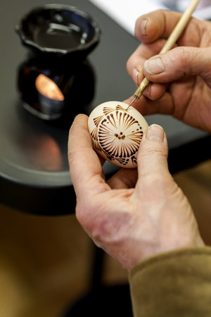 Close-up of a woman's hand painting an egg using beeswaxの写真素材
