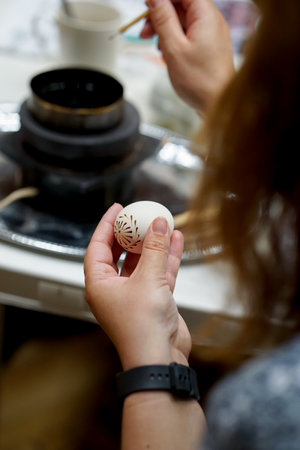 Woman decorating easter eggs in a pottery workshop, close upの写真素材