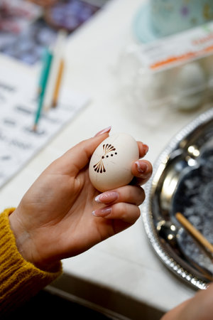 Easter egg in the hands of a young woman on the tableの写真素材