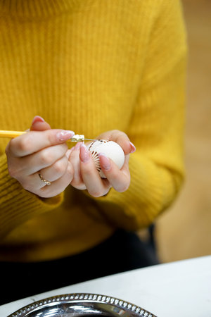 Easter egg in the hands of a girl in a yellow sweaterの写真素材