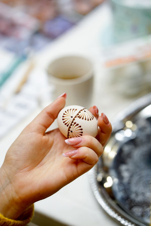 Easter egg in the hands of a young woman, close-up, painting with bees waxの写真素材