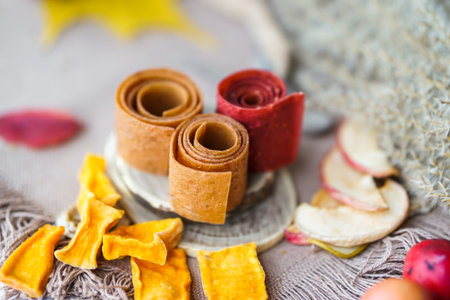 Autumn still life with apples, cinnamon sticks, dried fruit and berries rolls and dried leaves on a wooden backgroundの写真素材